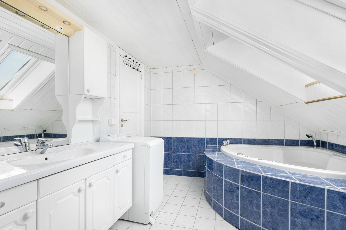 Det er dusjhjørne med buet front og skyvedør i glass. Badet har opplegg for vaskemaskin og et innfliset boblebadekar i hjørnet. Galleribilde