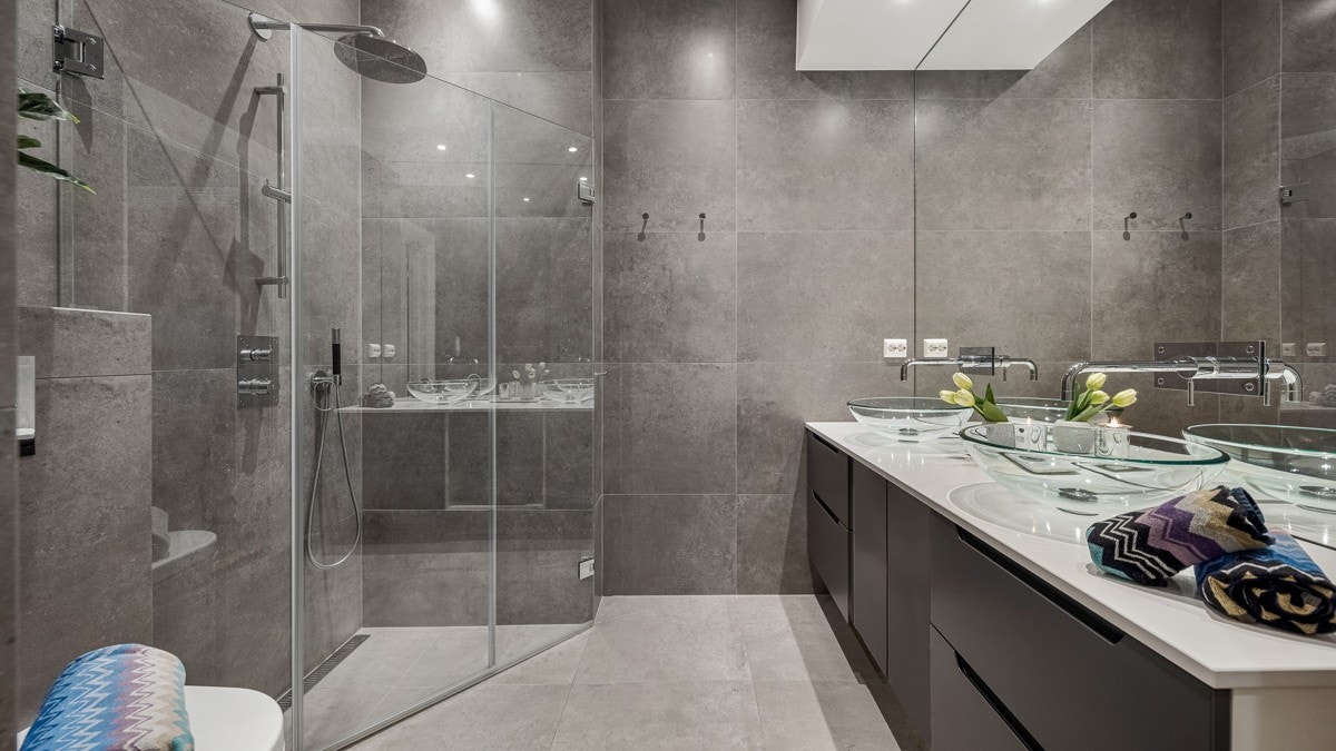 Badet som ligger i tilknytning til hovedsoverommet er innredet med en romslig regnfallsdusj, dobbelservant i glass og benkeplate i kompositt. Legg merke til Tapwell blandebatterier ut fra speilet og i dusjnisjen. Galleribilde