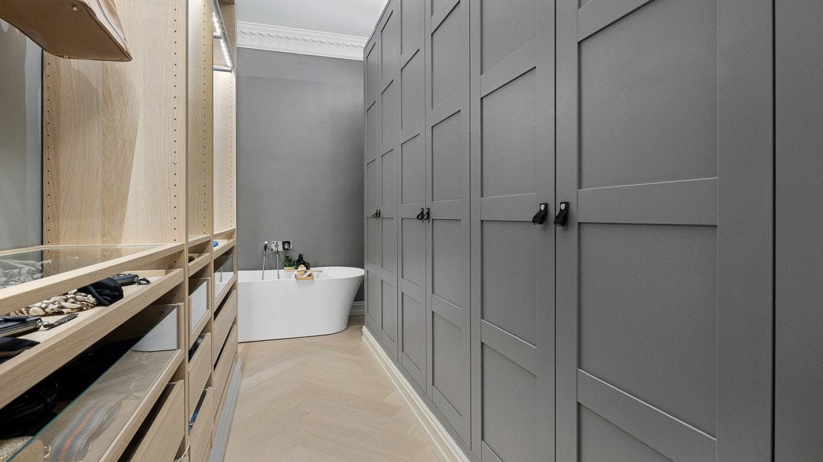 En stor walk-in-garderobe med snekkertilpassede garderobeskap og god belysing gir rikelig med plass til oppbevaring. Heldekkende speil på motsatt vegg. Eksklusivt badekar i silkestein. Galleribilde