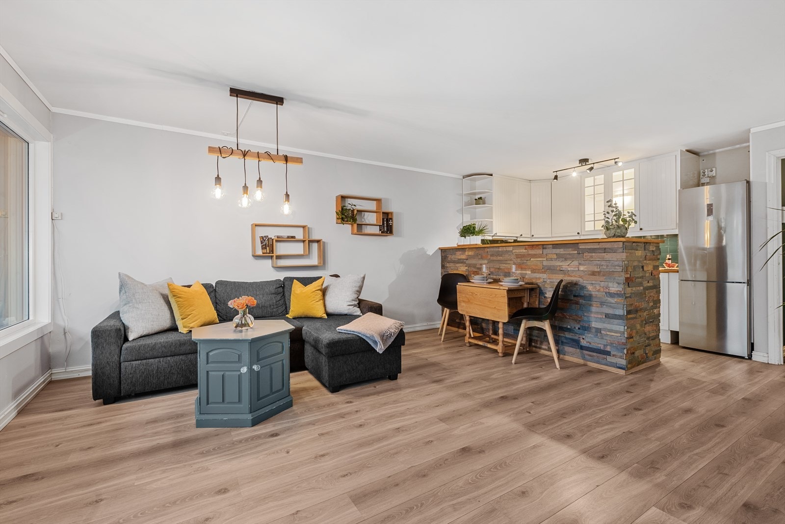 Lys og flott stue med åpen kjøkkenløsning - kjøkkenbenken skaper en fin romdeler mellom stue og kjøkken Galleribilde