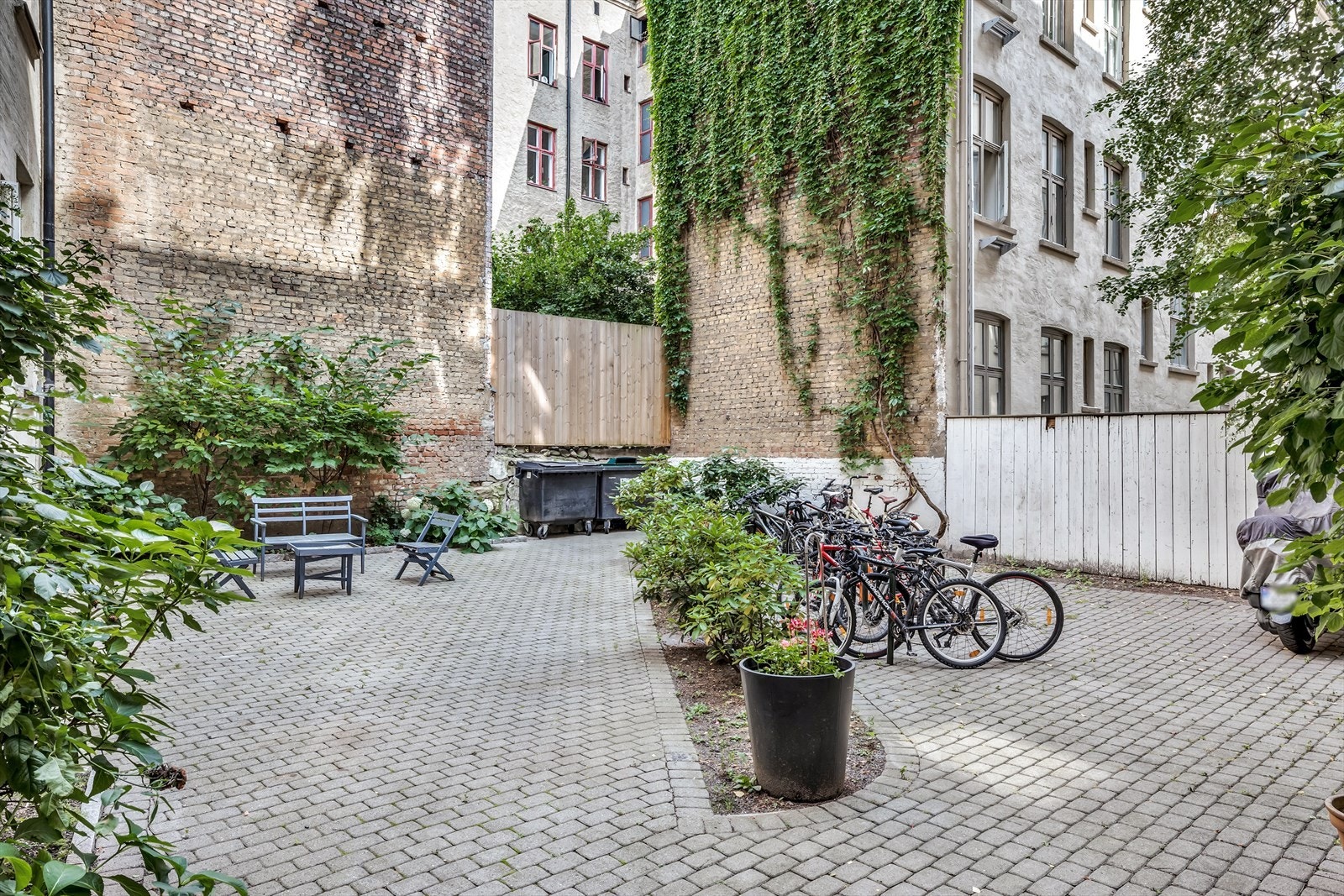 Sjarmerende bakgård med planter, busker, sitteplass og sykkelparkering Galleribilde