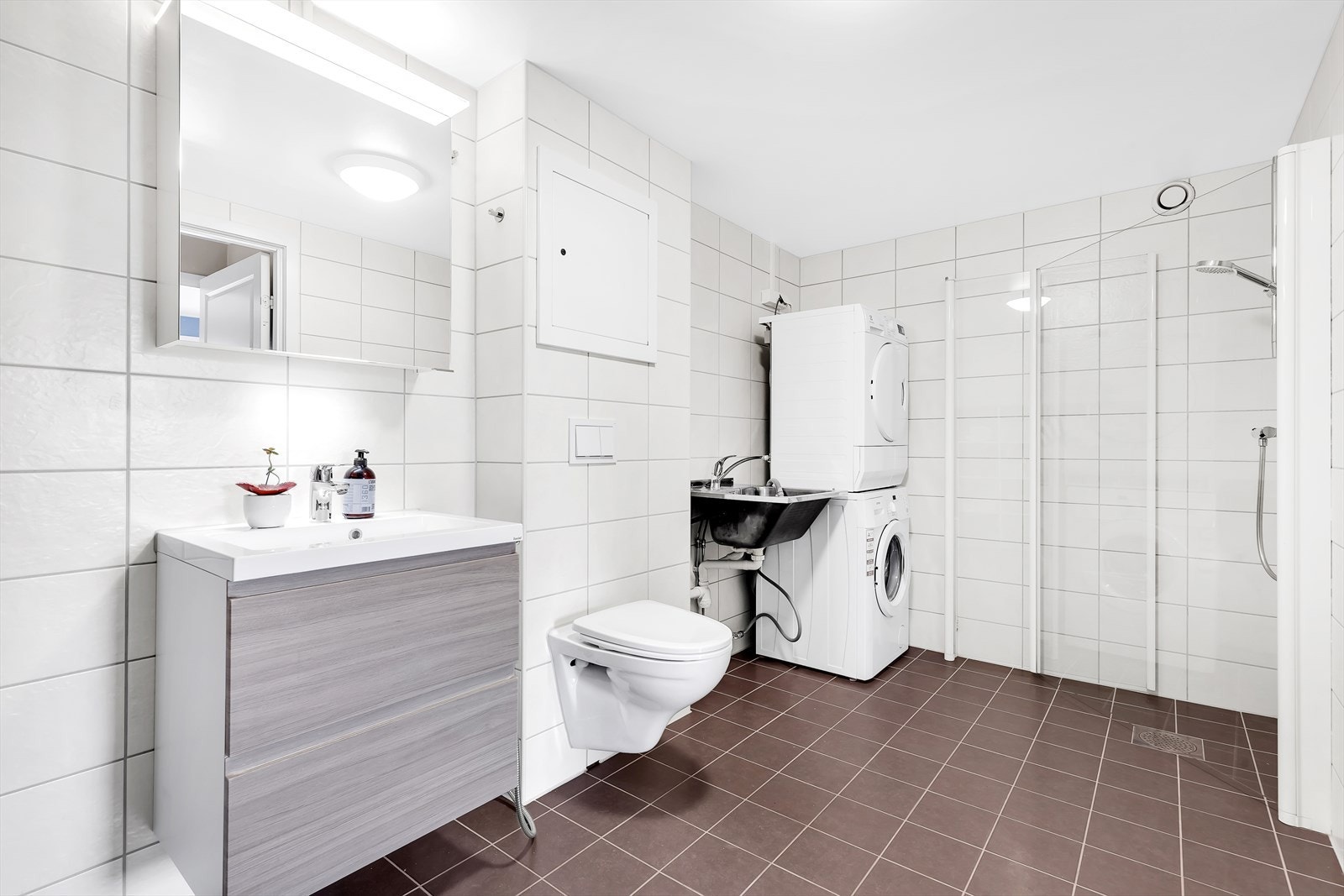 Baderomsinnredningen består av servant med skuffeseksjon, speil med overlys, vegghengt klosett, dusjhjørne med svingbare glassdører. På badet er det opplegg for vaskemaskin og stor utslagsvask. Galleribilde