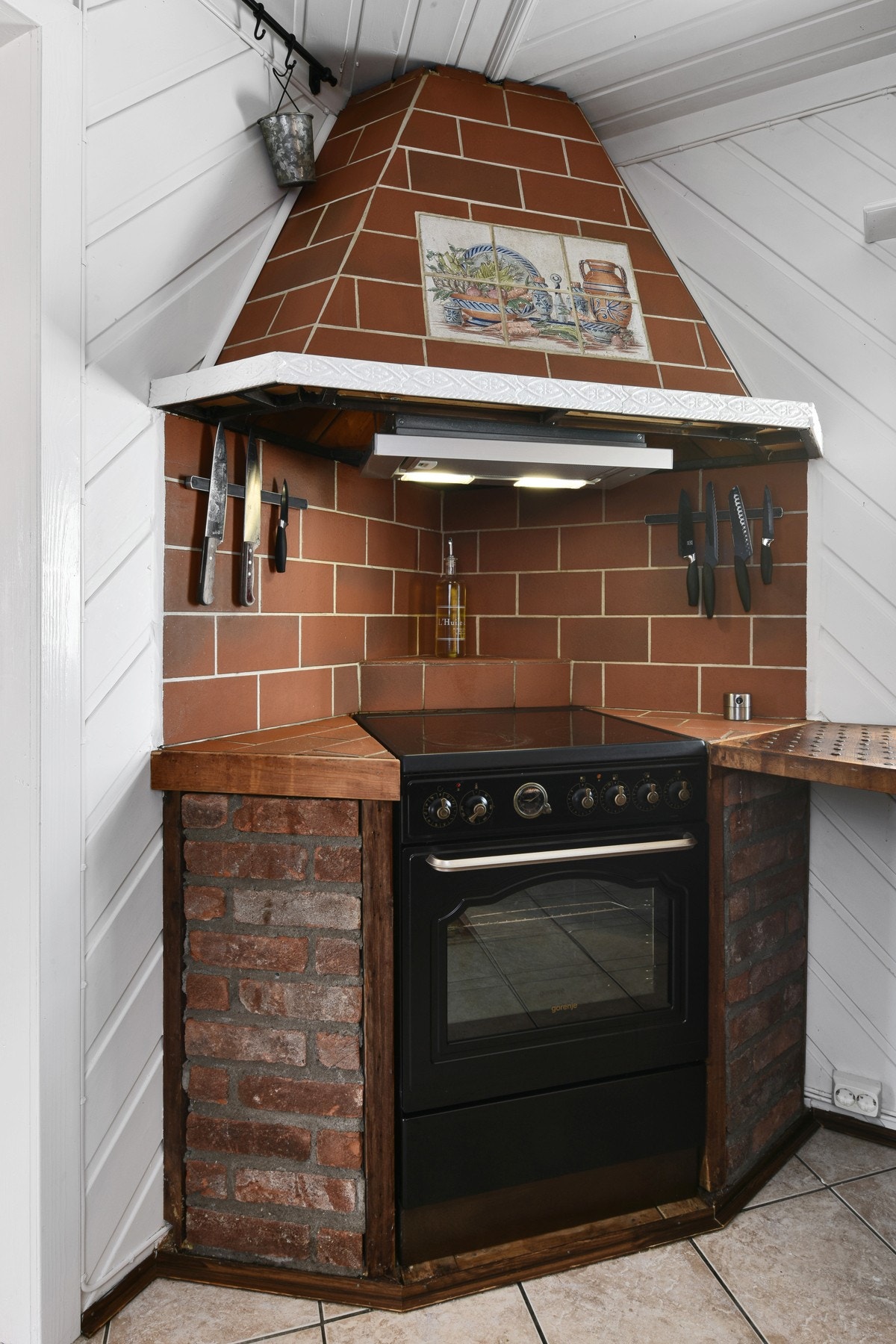 I hjørnet er det nisjer til komfyr, med teglstein på begge sider og flislagt ventilatorhette og vegg over. Galleribilde