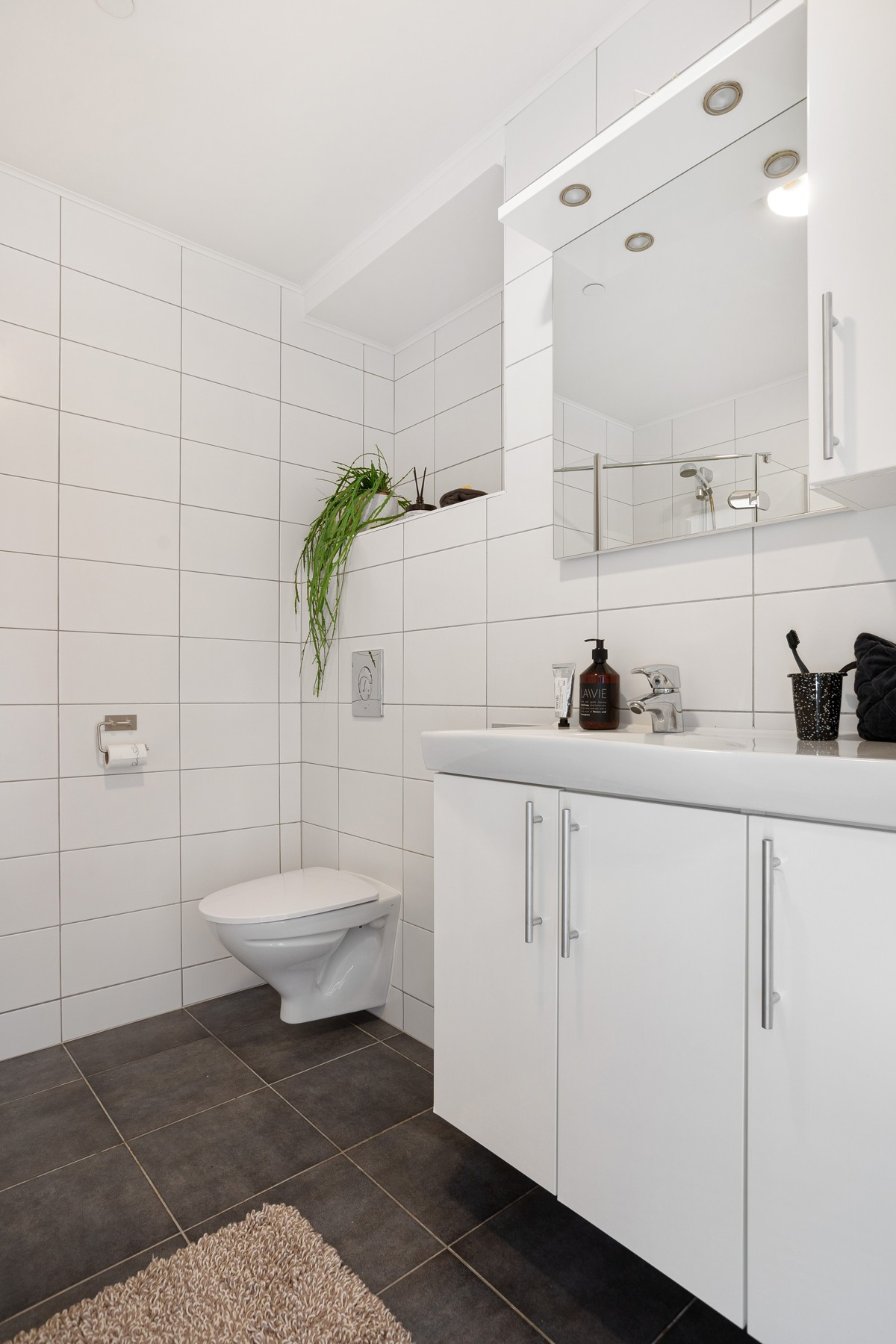 Badet er utstyrt med dusjhjørne, servant og vegghengt toalett