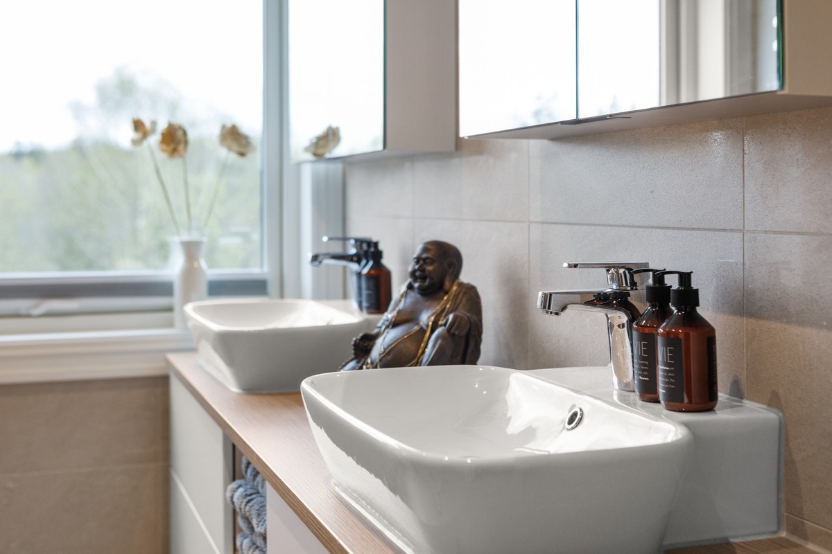 Badet er delikat innredet med dobbel servant på en moderne baderomsinnredning, overskap med speil og belysning. Galleribilde