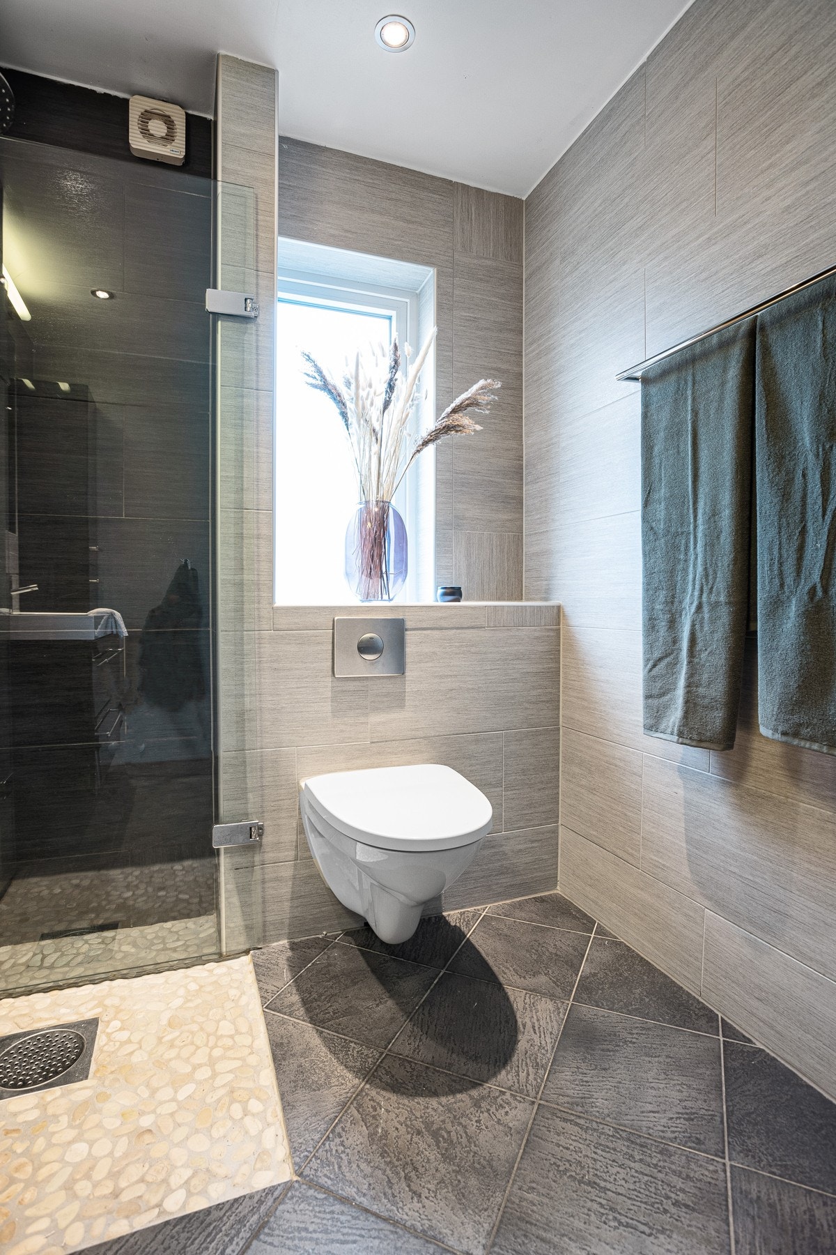 Videre er det dusjhjørne med foldbare dører, vegghengt toalett og varmekabler i gulv. Galleribilde