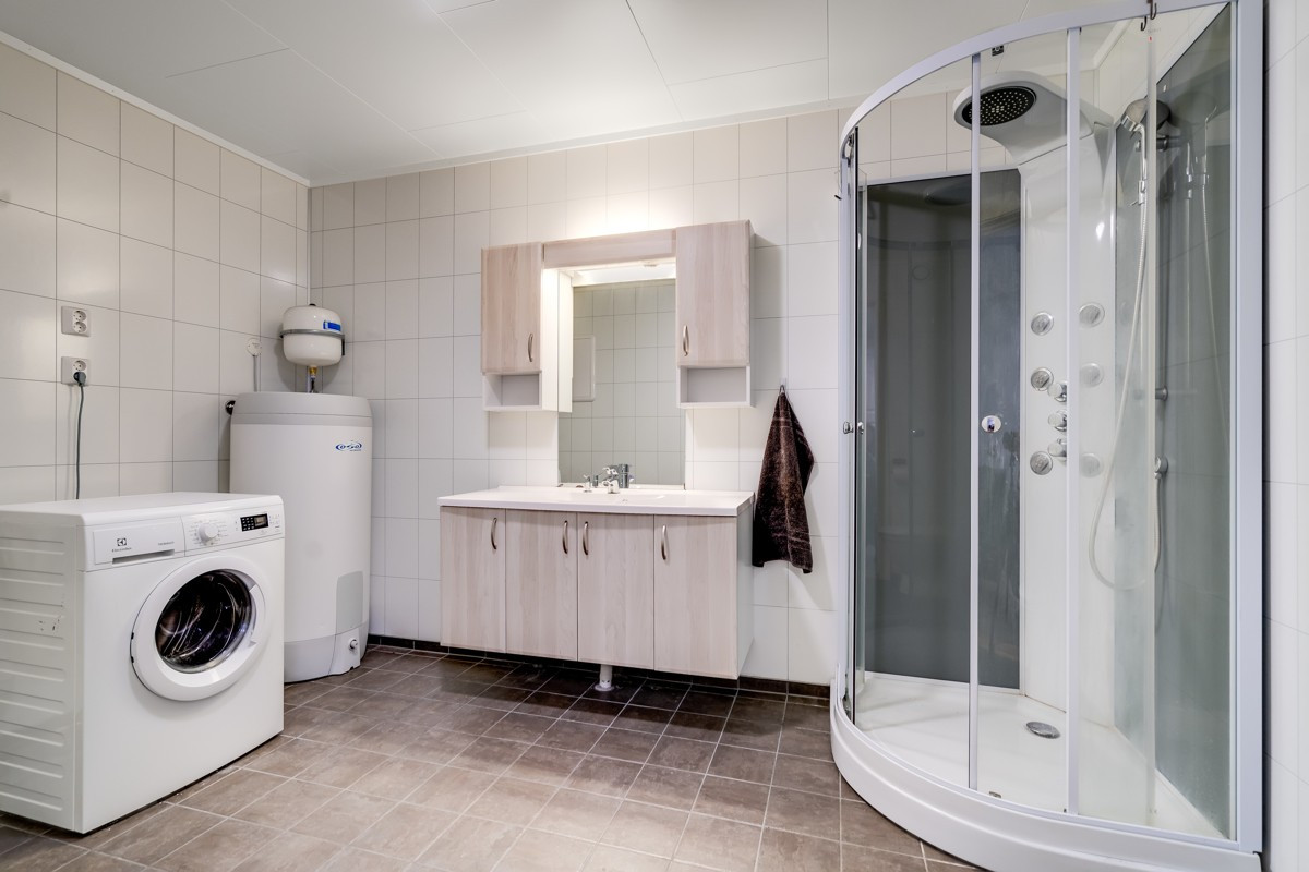 Badet er komplett flislagt med varmekabler i gulv - utstyrt med dusjkabinett, vegghengt toalett og heldekkende servant. Her er det opplegg for vaskemaskin