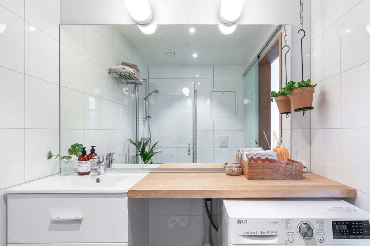 Servant med skuffer under og benkeplate i treverk, samt speil med belysning over benk. Galleribilde