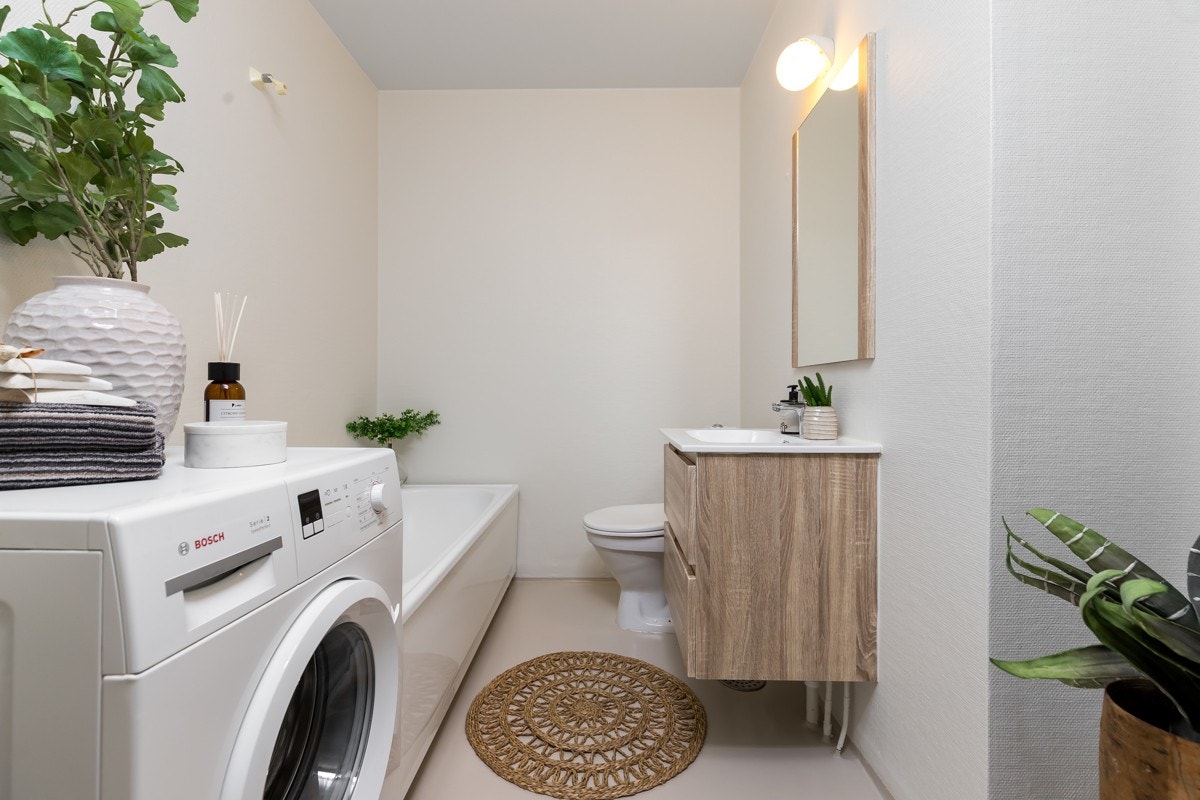 Bad med badekar, servant med underskap, speil, opplegg for vaskemaskin og wc. Galleribilde