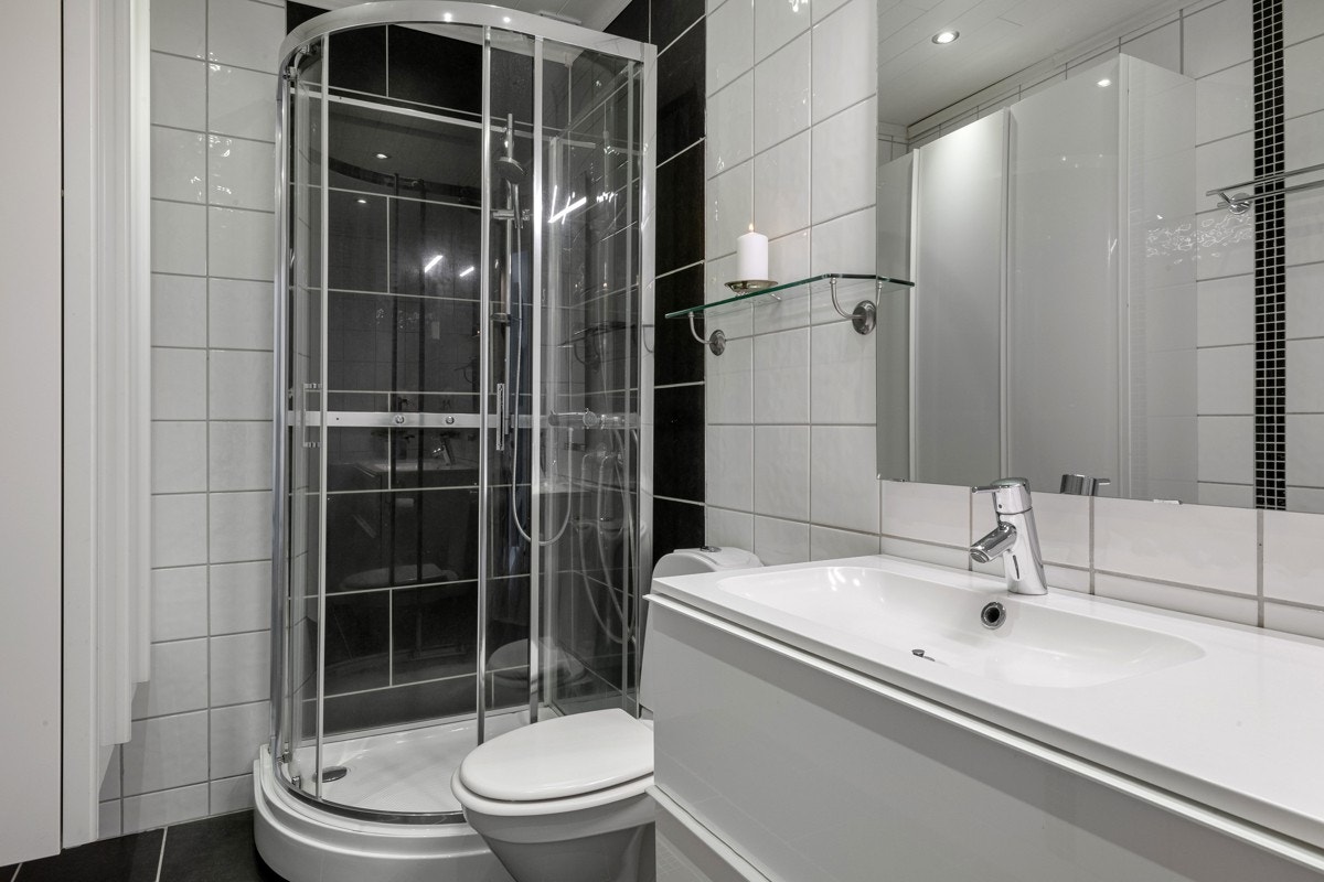 Badet er stilrent flislagt med sorte og hvite fliser. Galleribilde