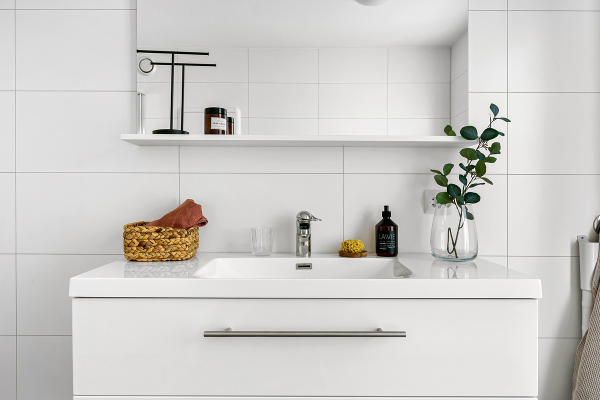 Badet er innredet med hvite fronter, servant, dusjhjørne og vegghengt toalett