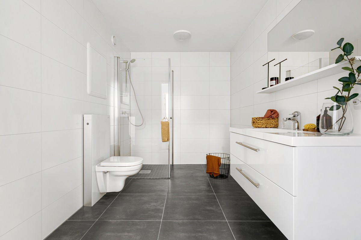 Badet har flislagt gulv med gulvvarme - her er det også opplegg for vaskemaskin