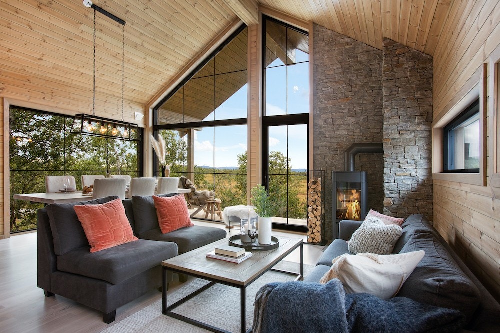 Illustrasjonsbilde (stuen i denne hytta er 60 cm bredere). Åpen stue/kjøkken-løsning, med høy takhøyde, store vinduer og fantastisk utsikt over fjellene. Galleribilde