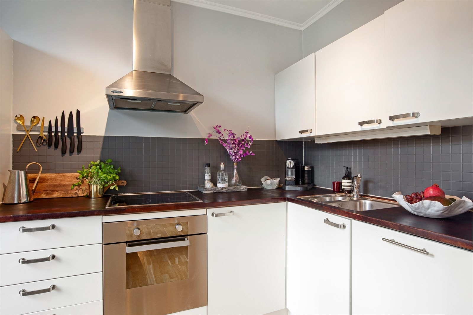 Pen kjøkkeninnredning med hvitefronter, benkeplate i heltre og integrerte hvitevarer Galleribilde