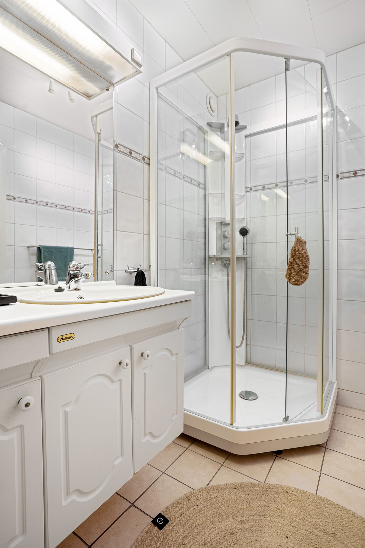 Badet er utstyrt med dusjkabinett, toalett og servant med god skapplass.