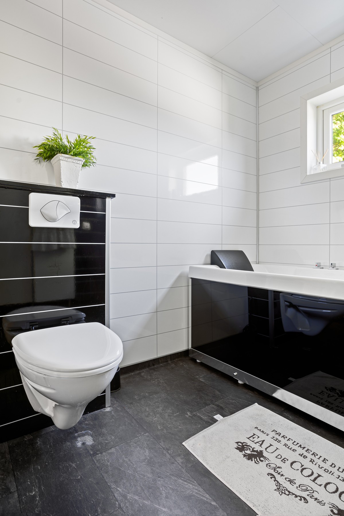 Badet er utstyrt med badekar, vegghengt toalett og servant