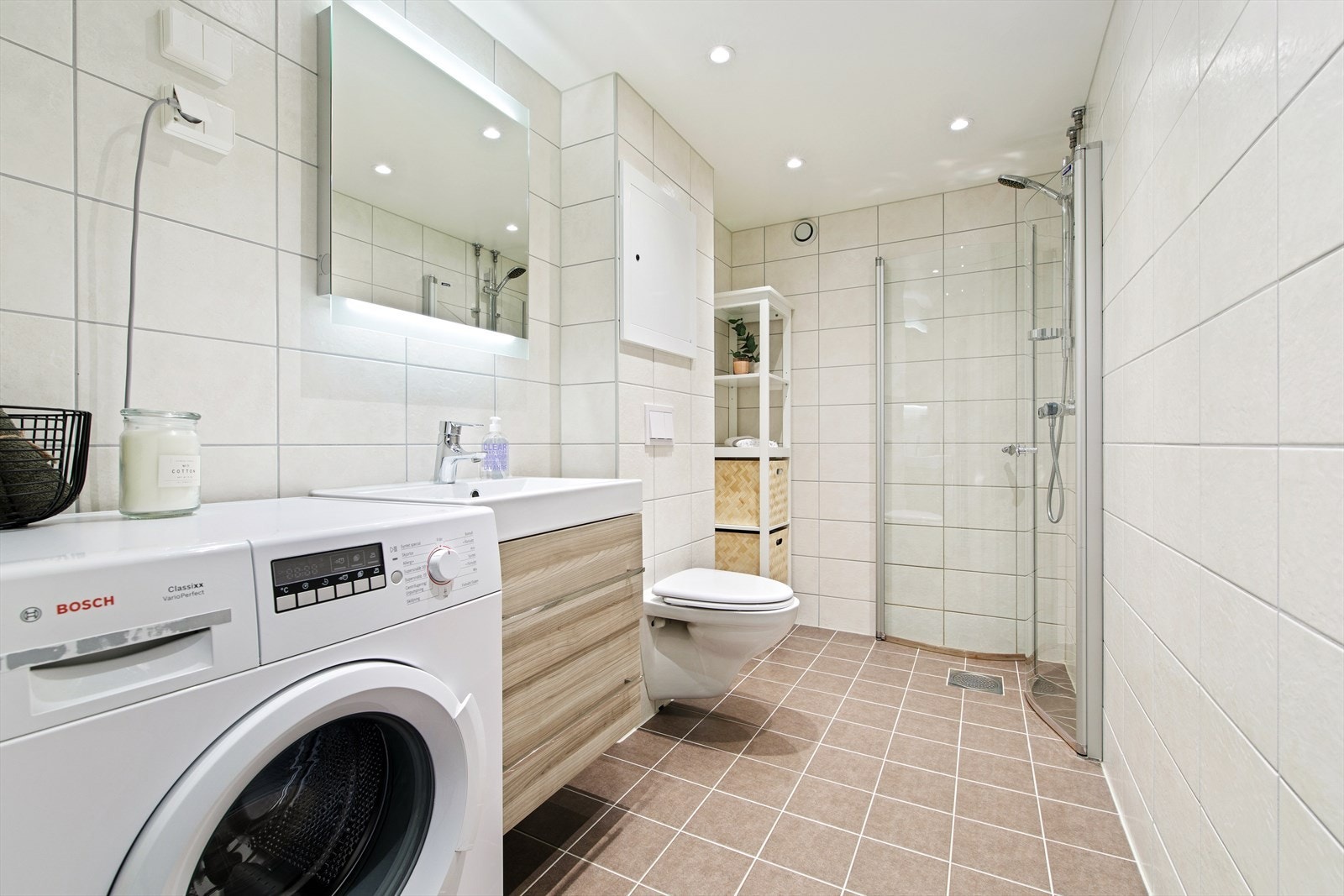 Badet ble totalrenovert i regi av borettslaget i 2018. Baderommet er innredet med lyse fliser på veggene og brune fliser over varmekabler på gulvet. Galleribilde