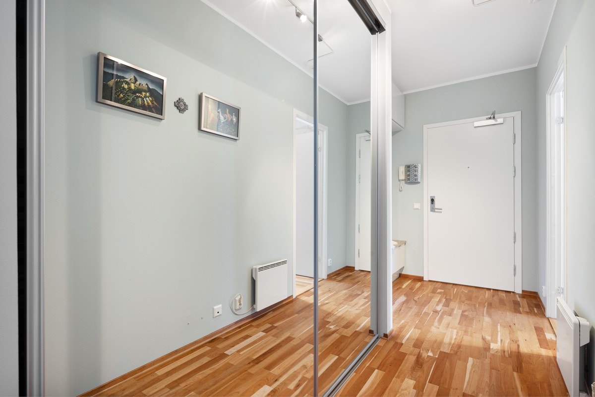 Romslig entrè med stor 1 meter dyp skyvedørsgarderobe med speilfronter Galleribilde