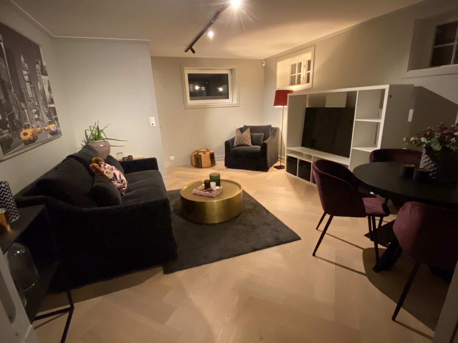 Stue med stor TV-rack, godestol og deilig sofa i myk fløyel, samt rundt spisebord med spisestoler Galleribilde