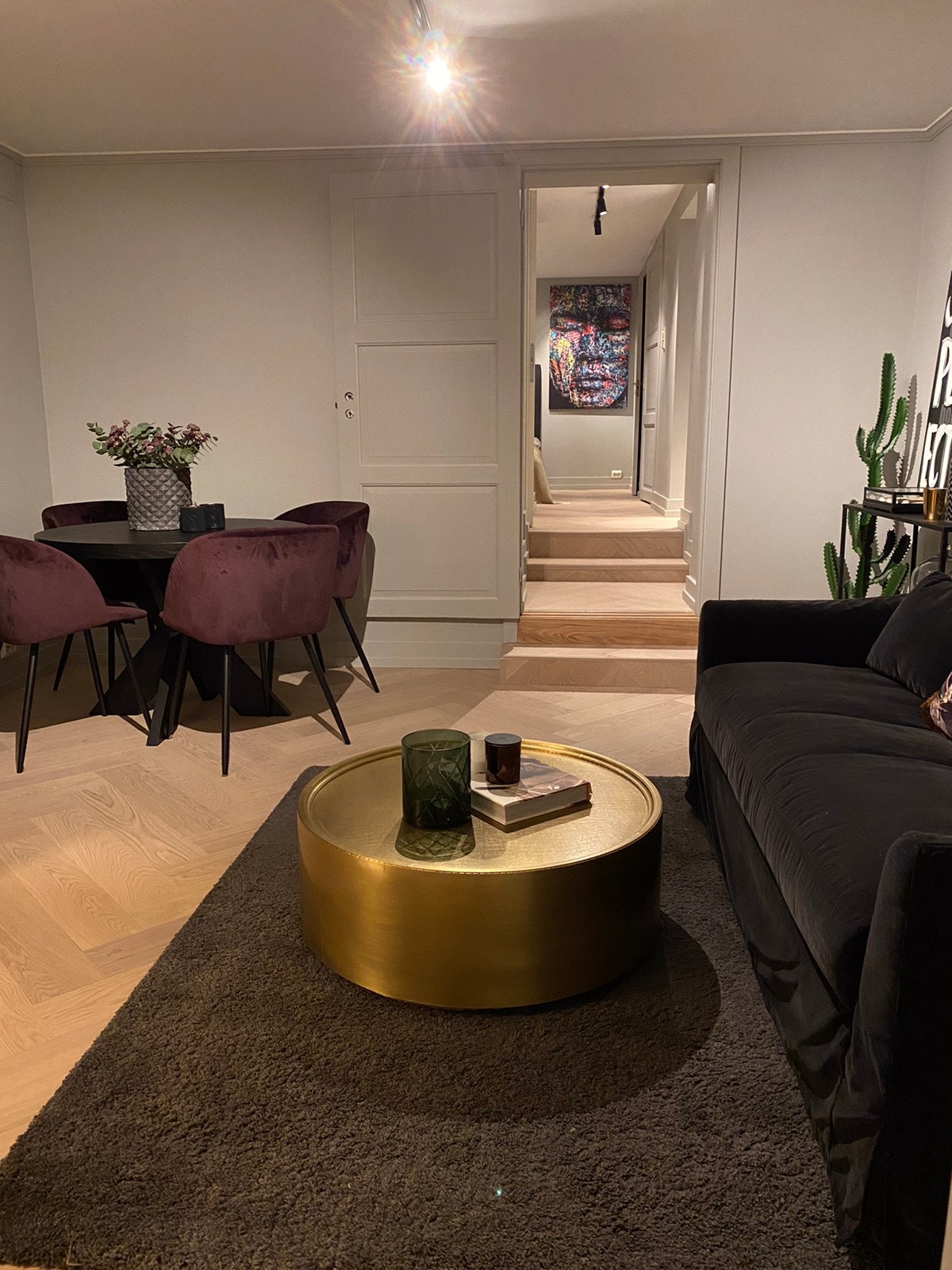 Stue med stor TV-rack, godestol og deilig sofa i myk fløyel, samt rundt spisebord med spisestoler Galleribilde