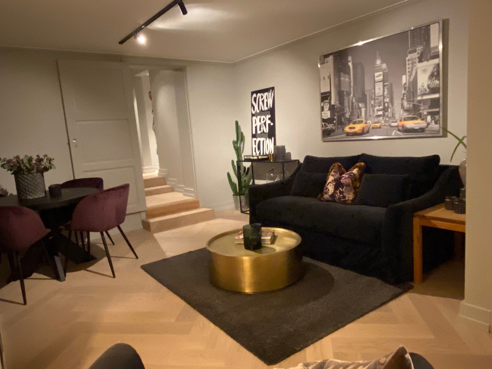 Stue med stor TV-rack, godestol og deilig sofa i myk fløyel, samt rundt spisebord med spisestoler Galleribilde