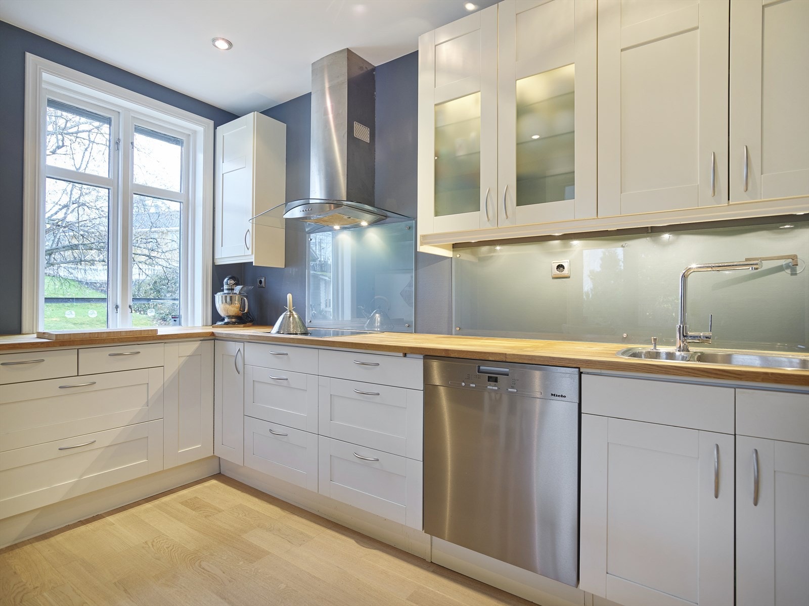 Kjøkkeninnredning med malte, profilerte fronter. Benkeplate i heltre. Galleribilde