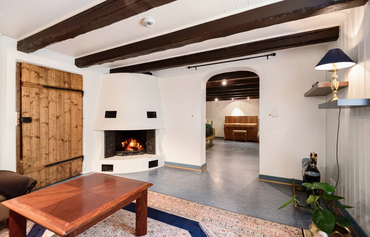 Felles for rommene er mørke, solide takbjelker som står i lekker kontrast til ellers lysmalte overflater i panel. I kjellerstuen er det også hjørnepeis som står for lun atmosfære vinterstid. Galleribilde