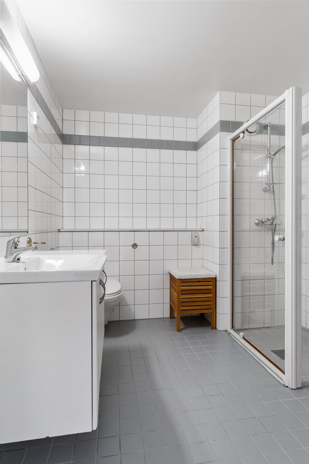 Baderomsinnredning med heldekkende servant, speil og veggmontert klosett. Galleribilde