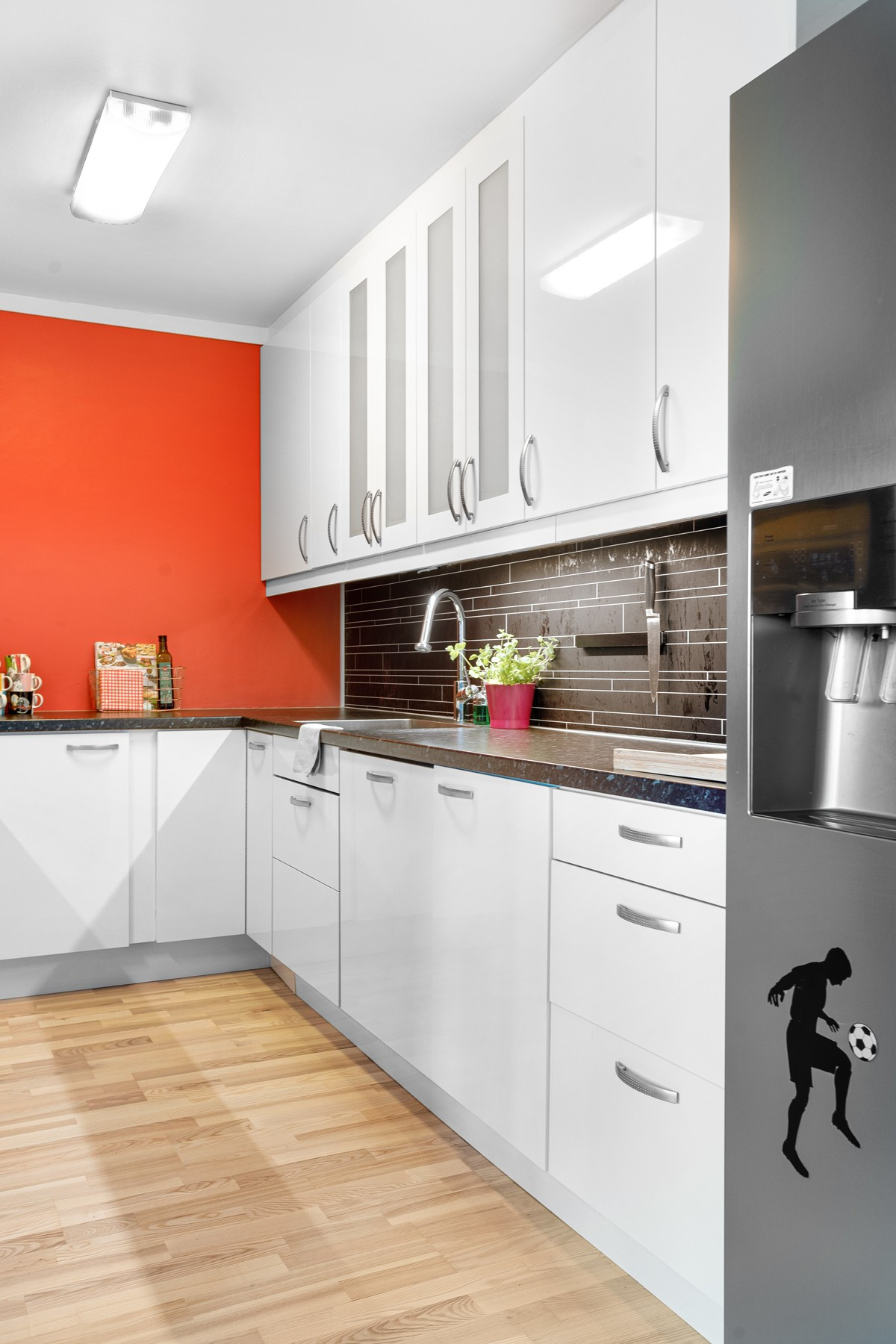 Kjøkkenet er innredet med hvite fronter, kitchenboards på vegg over benk og en sprek farge på veggen.