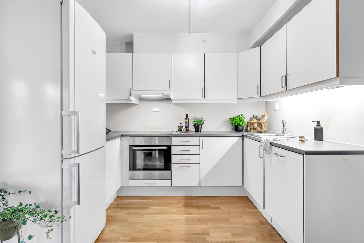 Stilrent og tidløst kjøkken som har innredning med hvite og slette fronter, samt benkeplate av laminat. Galleribilde