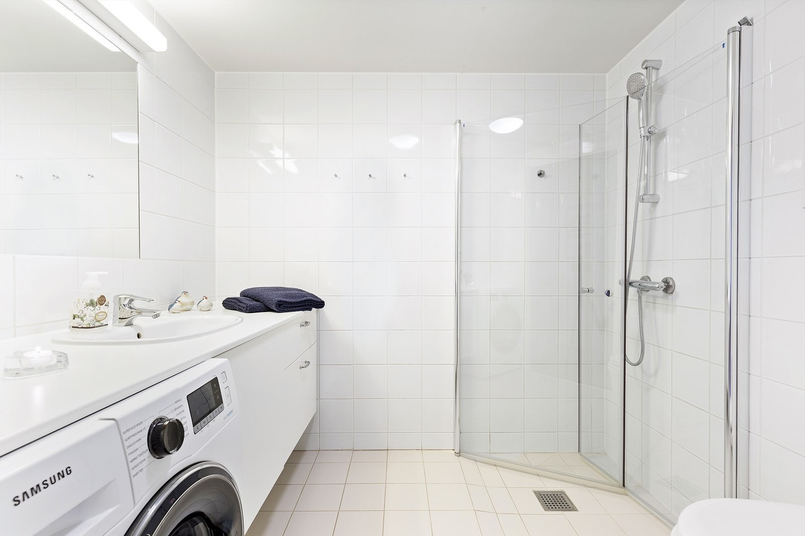 Innredet med veggintegrert speil, dusjhjørne, vegghengt WC og speilskap. Galleribilde