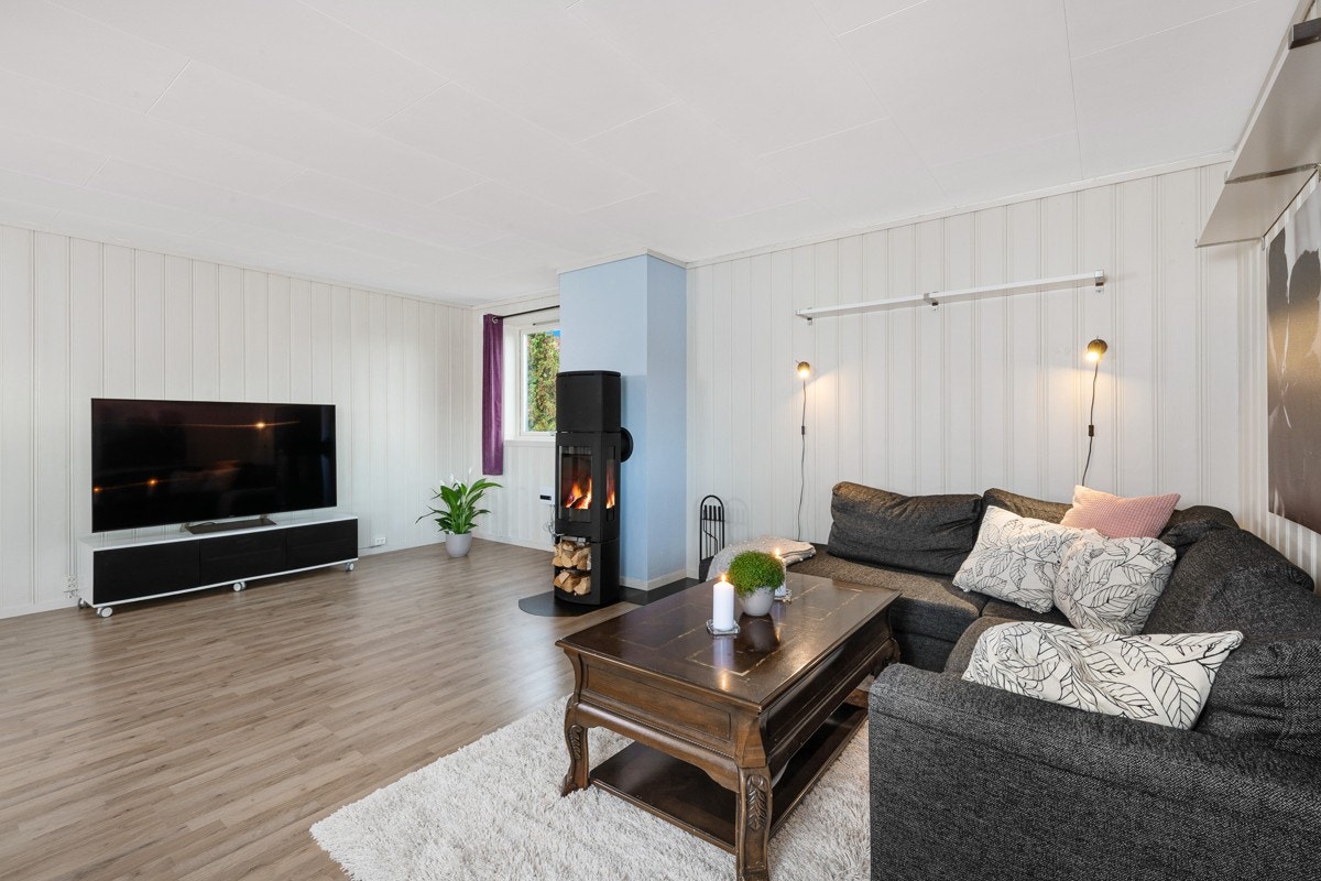Rommet har laminatgulv, hvitmalt panel på veggene i stuedelen og slette, mintgrønne på vegger i kjøkkendelen. Galleribilde