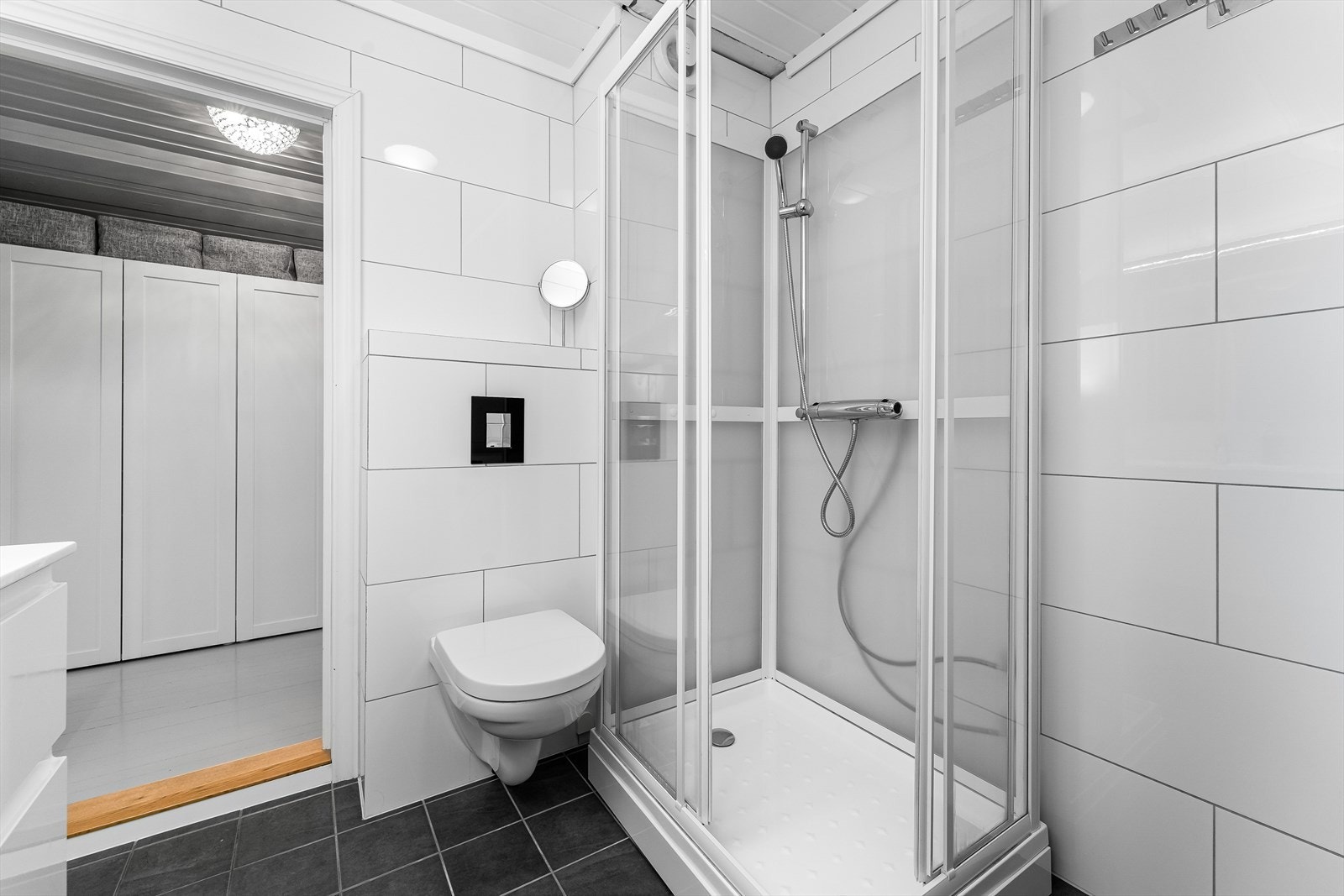 Badet er innredet med heldekkende servant i møblement, speil med belysning i 2019, sideskap i 2016, vegghengt toalett i 2013 med ny trykknapp i 2019 og nytt dusjkabinett i 2016. Galleribilde