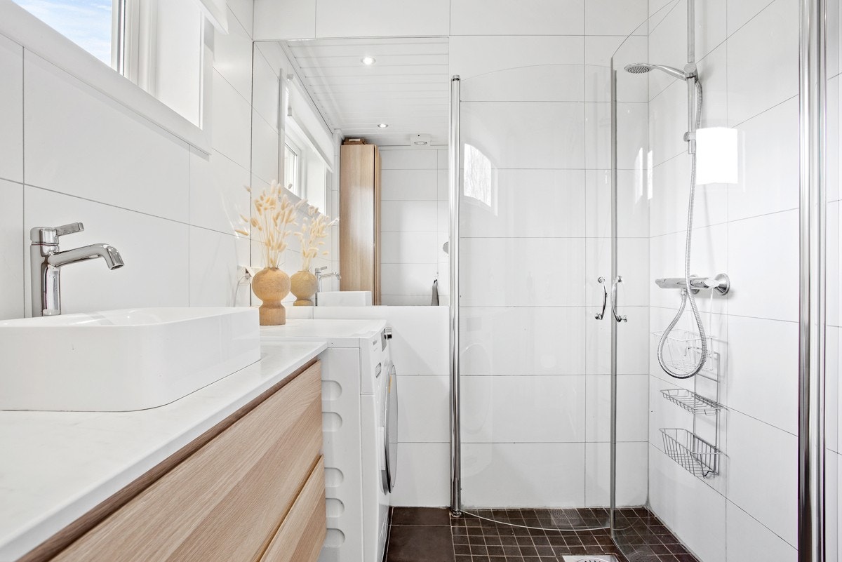 Rommet har ellers innfliset speil, veggmontert toalett, innfellbare dusjdører og opplegg for vaskemaskin. Galleribilde