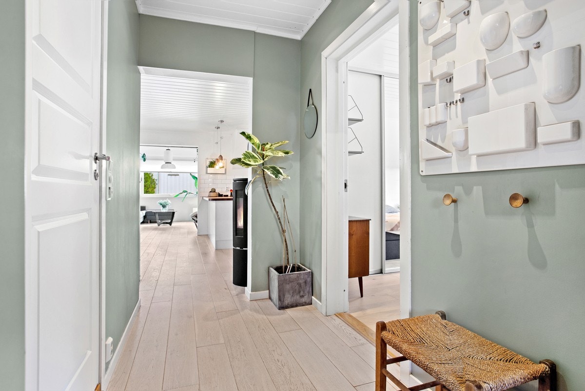 Videre inn ligger en innbydende entré med enstavs parkett på gulv og dus grønnfarge på veggene. Galleribilde
