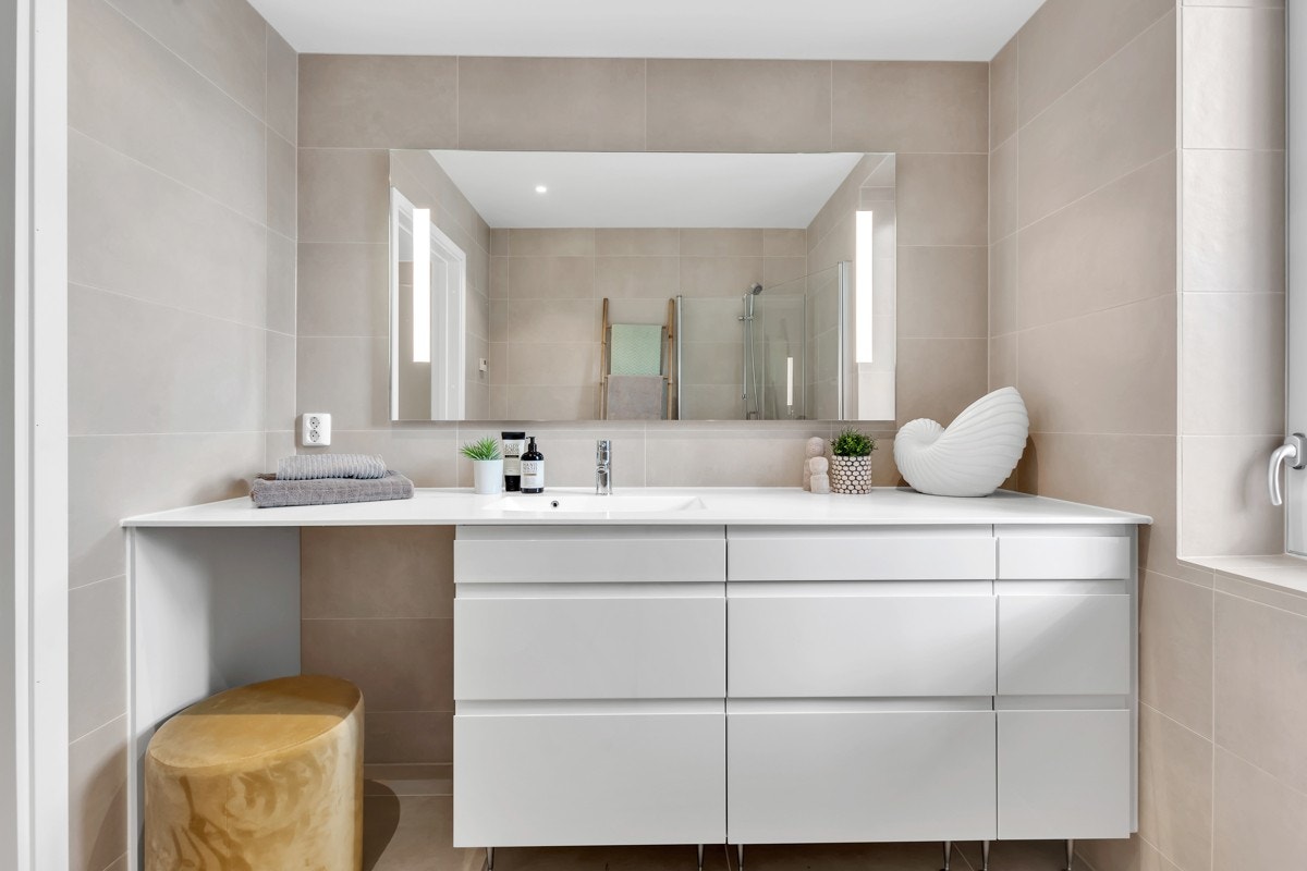 Flott hovedbad med sandfargede fliser, gulvvarme og downlights. Galleribilde