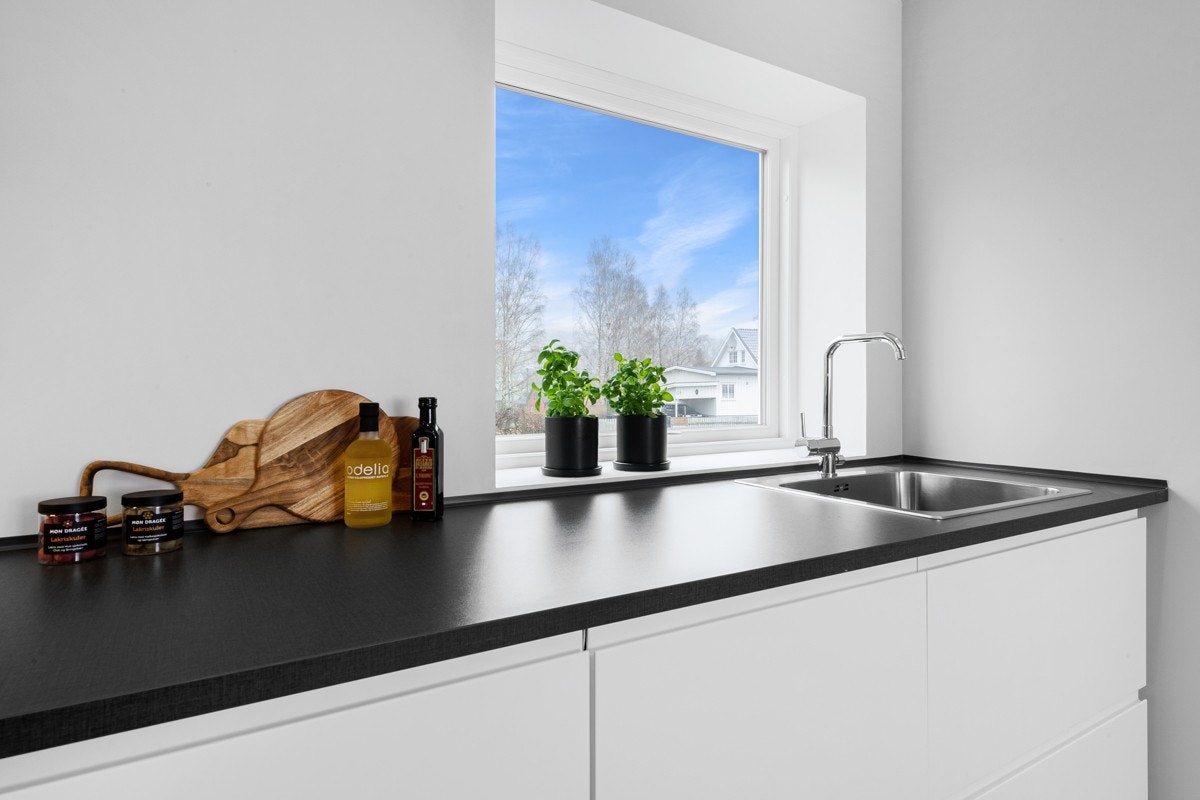 Den mørkegrå laminatbenkeplaten har nedfelt oppvaskkum i stål. Galleribilde