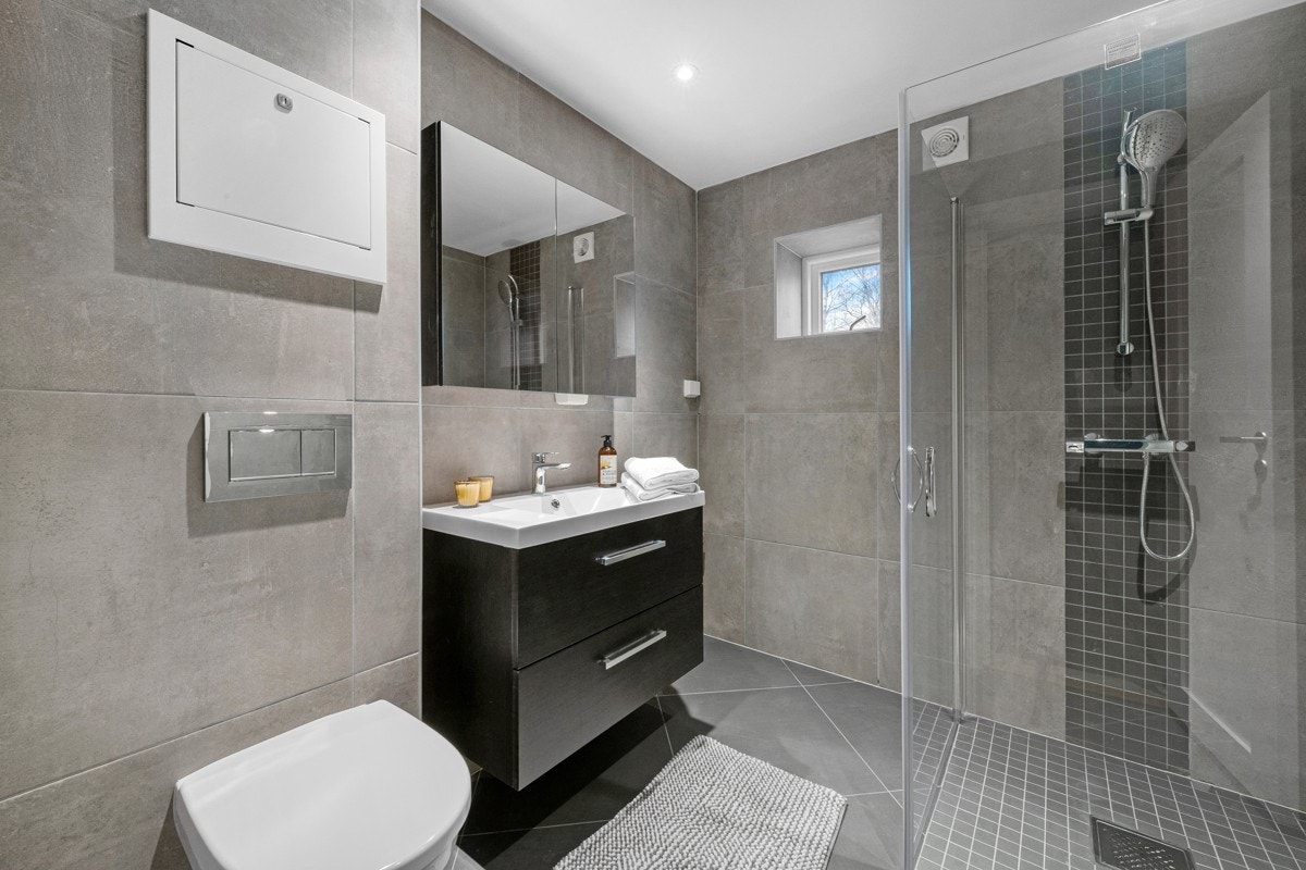 Rommet har downlights i himlingen, grå fliser på veggene og matchende fliser på gulv med gulvvarme. Galleribilde