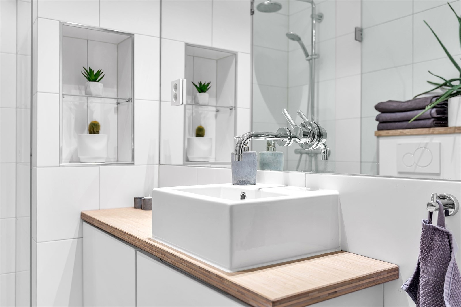 Badet er utstyrt med dusjnisje med glassvegg og regndusj, veggehengt wc og servantinnredning med skuffer. Galleribilde