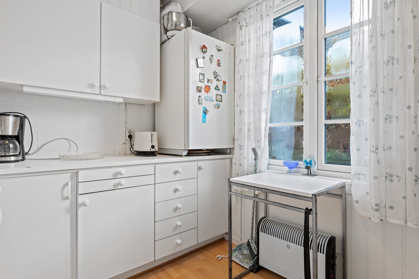 Kjøkken på ca. 6,40 m². Innredning med lyse slette fronter og hvit laminat benkeplate med fliser over Galleribilde