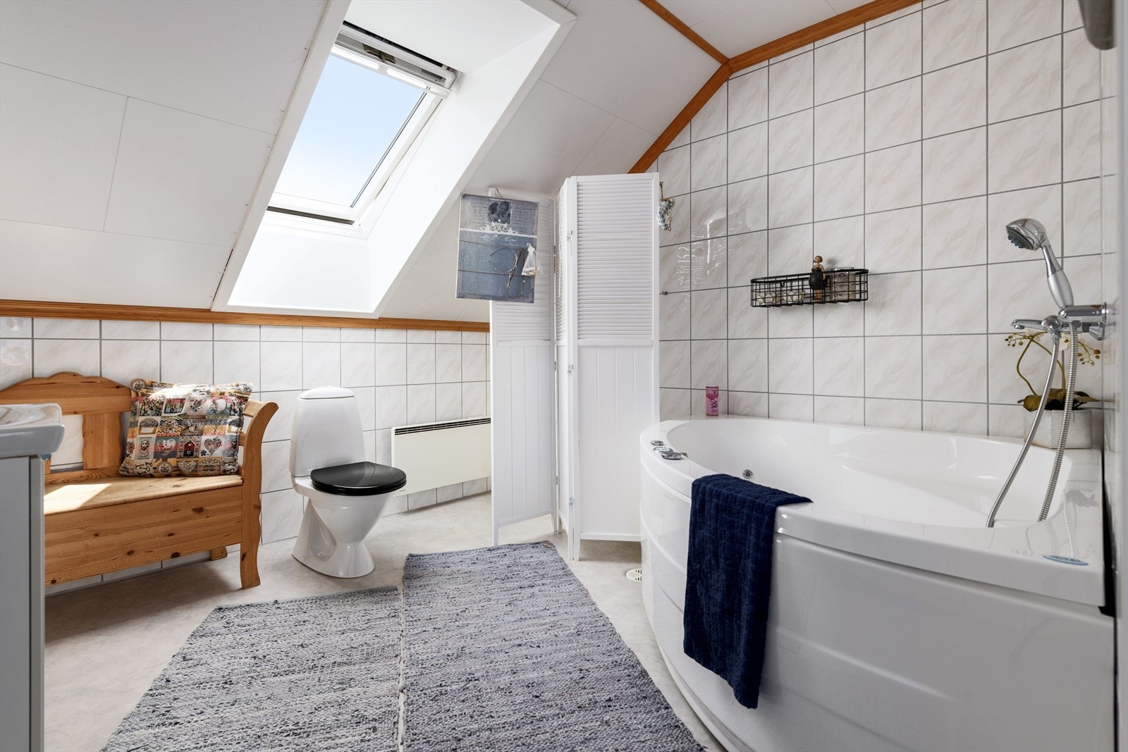 Badet i andre etasje er romslig. Det har et lyst gulvbelegg, vegger lagt med lyse fliser, og mønt himling med takvindu. Galleribilde