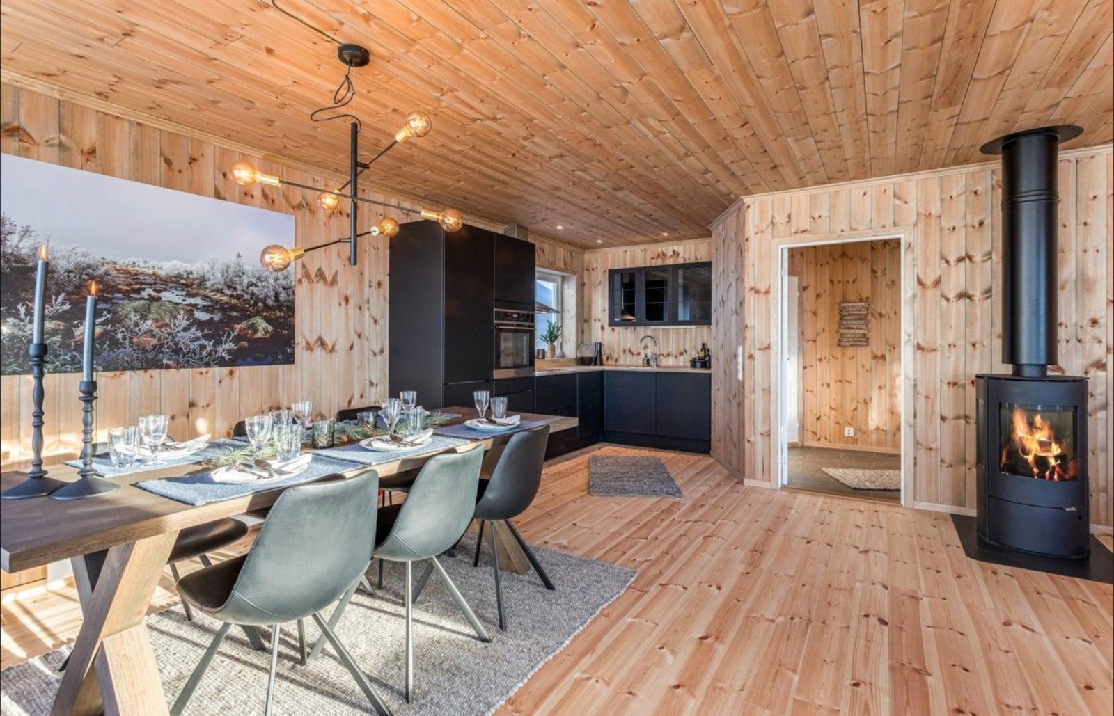 Kundetilpasset innredet hytte med ferdigbeiset panel ellers standard inndeling.
Her fra spiseplass mot kjøkken. Galleribilde