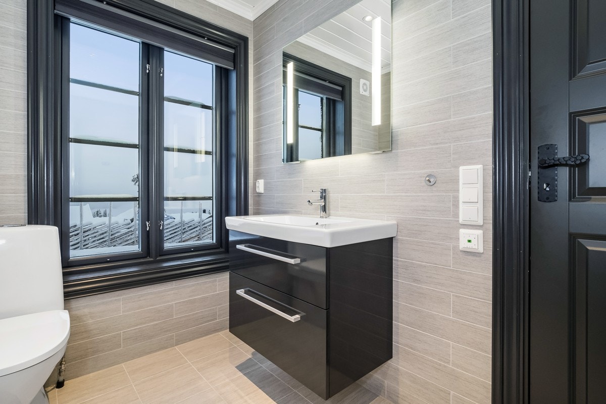 Dette badet er innredet med toalett, servant med skuffer under og dusjhjørne med innfellbare glassdører. Galleribilde