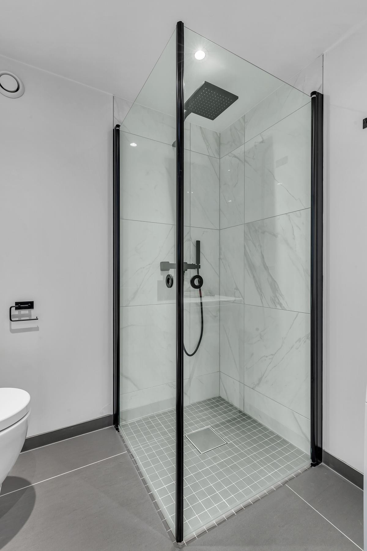 Dusjhjørnet er utstyrt med innfellbare glassdører med sort ramme og deilig regnfallsdusj Galleribilde