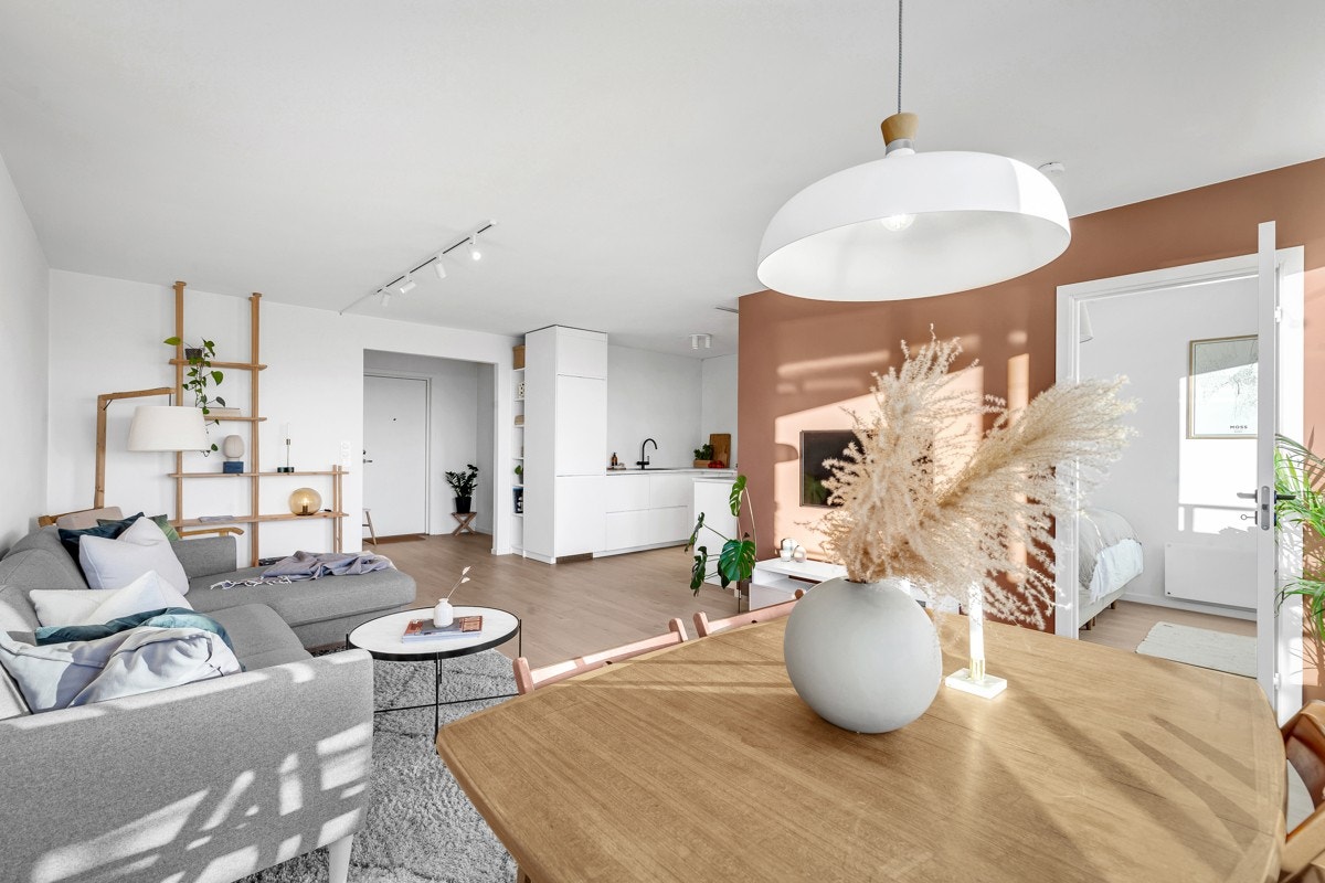 Leiligheten har en luftig stue i åpen løsning med et moderne kjøkken Galleribilde
