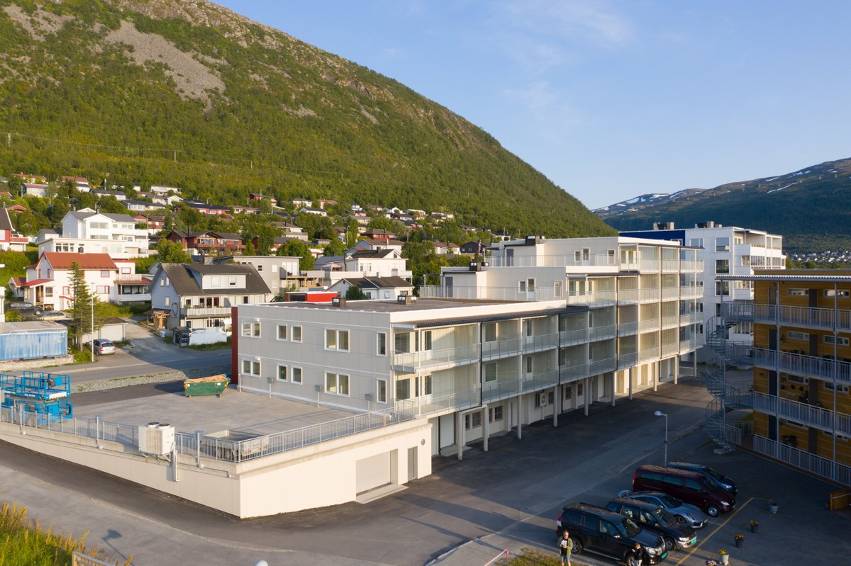 Fasade sett fra forsiden, med innkjøring til garasjeanlegg og parkeringsplasser