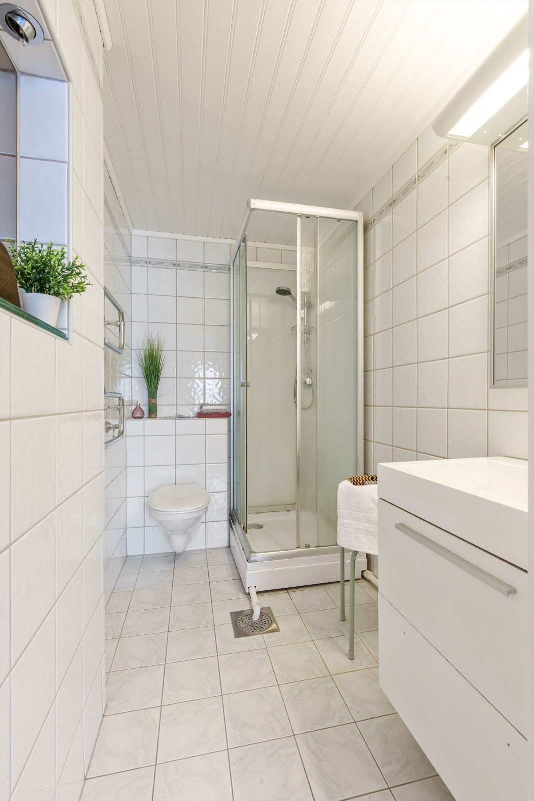 Det ene badet ligger i tilknytning til hovedsoverommet og har lyse fliser på gulv og vegger, gulvvarme, dusjkabinett, elektrisk avtrekksvifte og et veggmontert toalett. Galleribilde