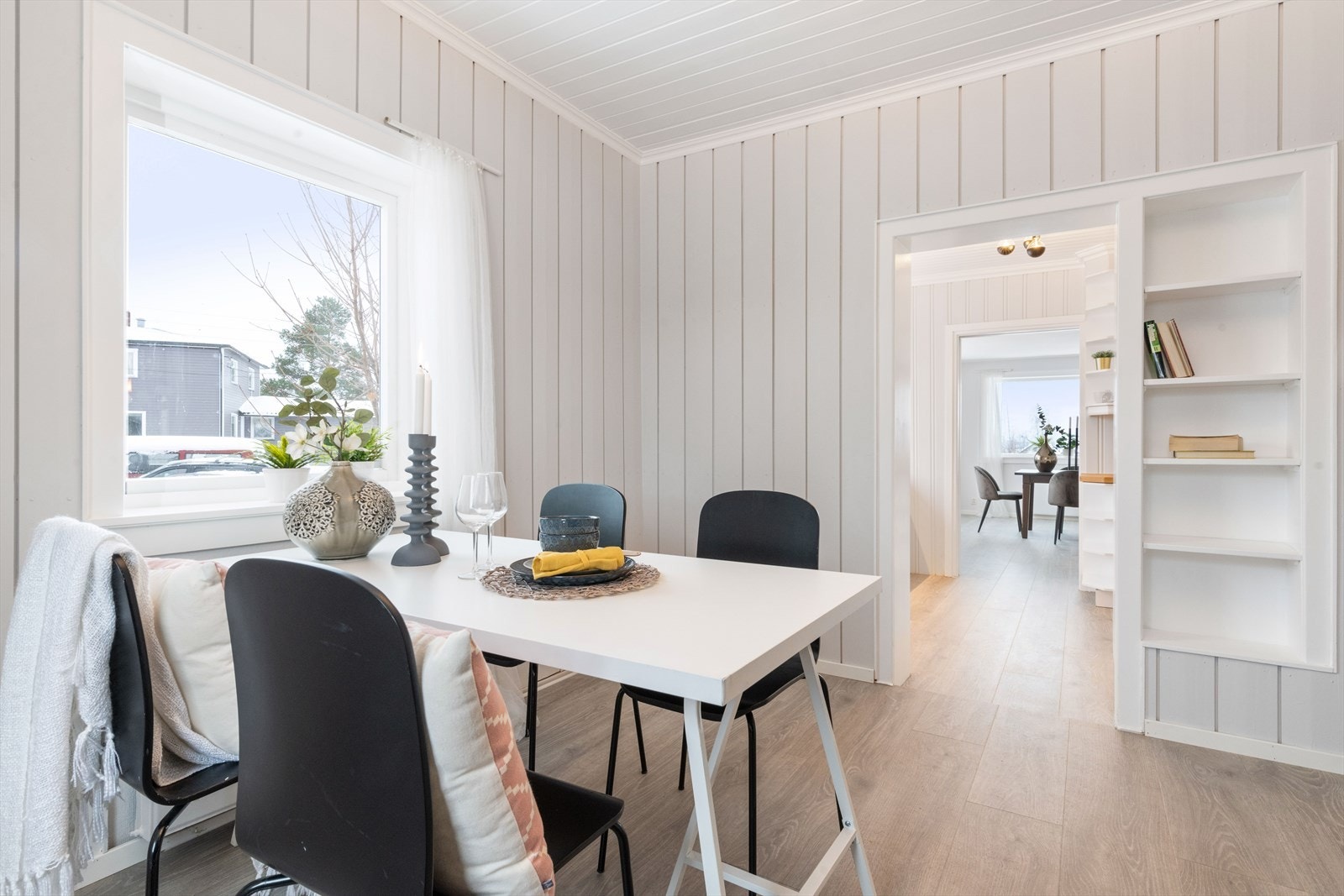Fra kjøkkenet er det åpning ut mot en koselig, liten spisestue med enstavs laminatgulv, lysmalte panelvegger og store vinduer. Galleribilde