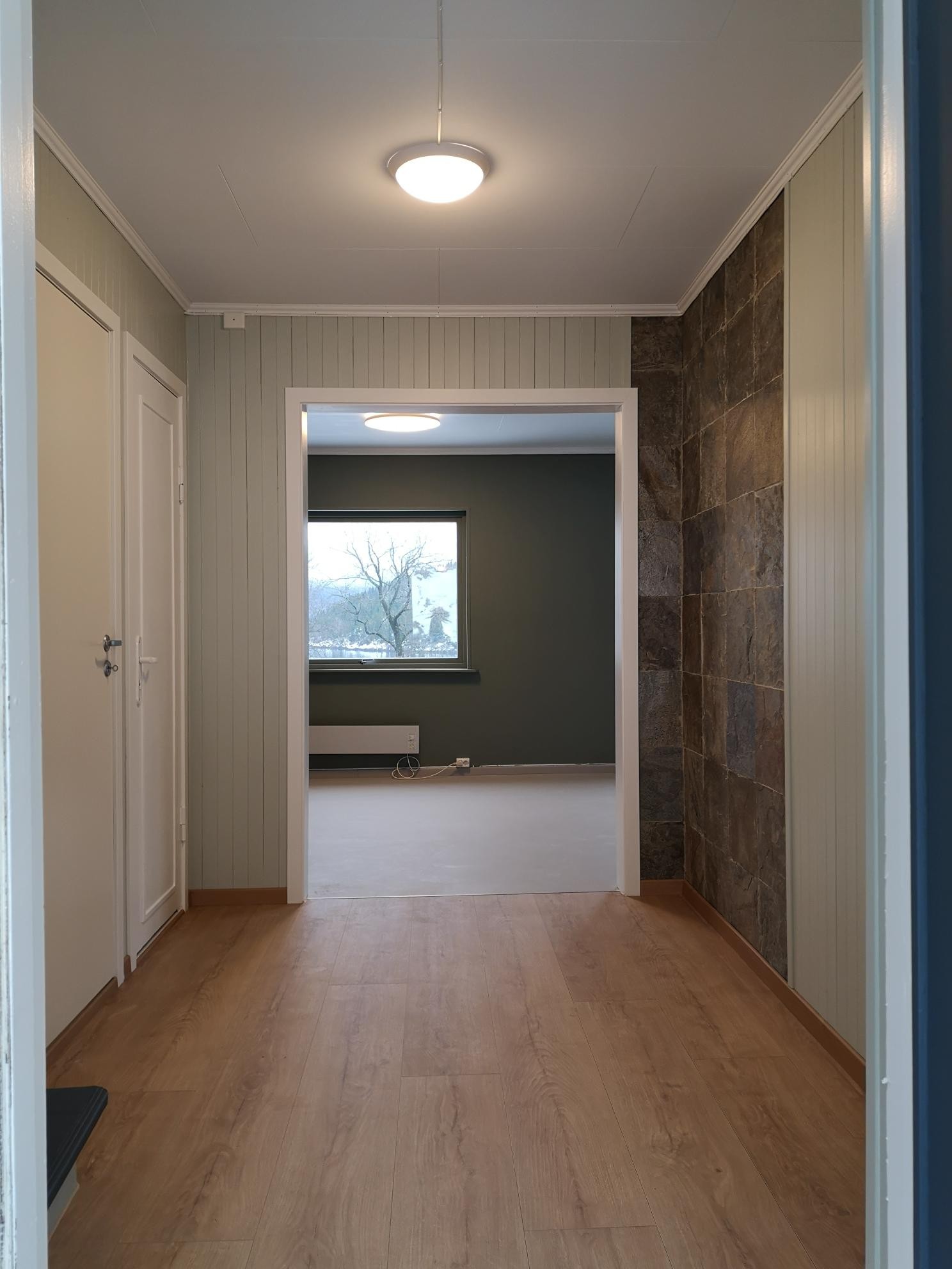 Velkommen inn! Gangen, med nytt gulv og varmekabler fra 2020. Åpent inn til kjøkken/stue. Vaskerom og toalett til vestre. Galleribilde