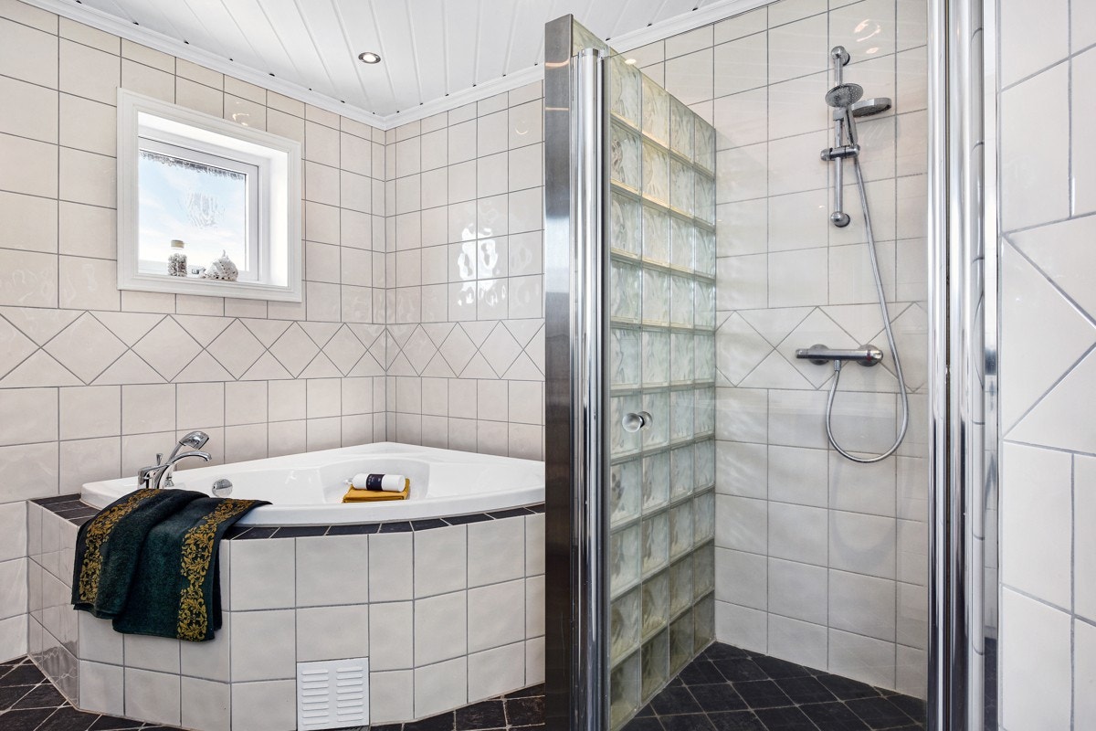 Badet i første etasje har mørke fliser på gulvet, lyse fliser på veggene, gulvvarme og dimbare downlights. Galleribilde